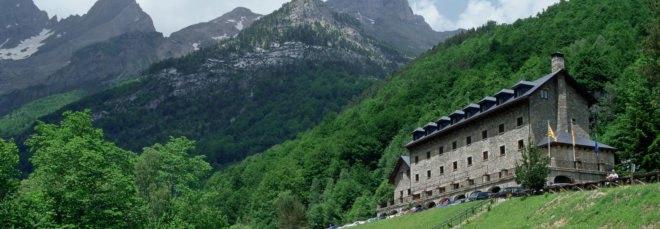 stone hotel with gabled roof on a hill with mountains in background