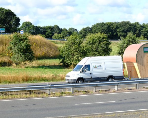 white van pulling wood tiny home on country road