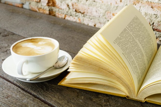 latte in white mug next to open book