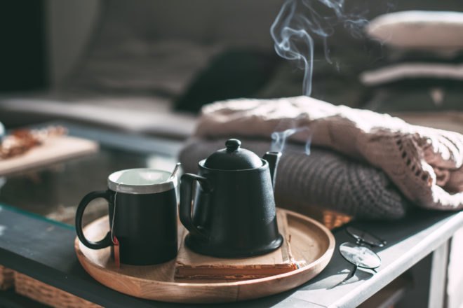 steaming tea pot and mug of tea on tray in a living room