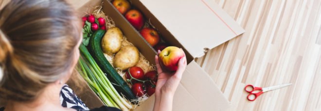 woman looking at box of produce