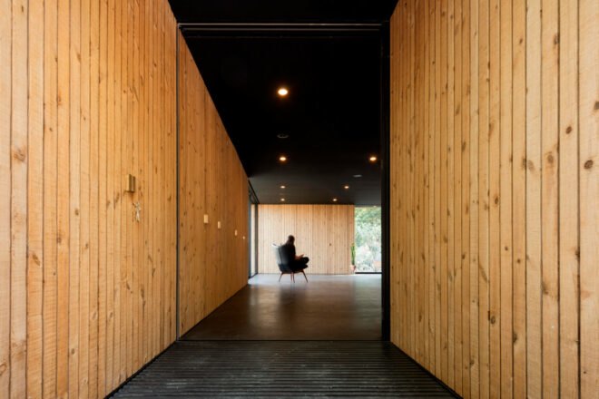 woman's figure sitting in chair inside a dark timber room