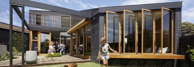 renovated 1960s home surrounded by lush greenery under blue skies with children playing outside