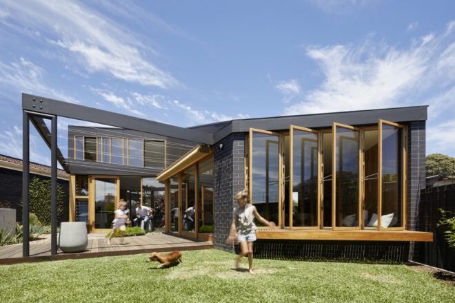 renovated 1960s home surrounded by lush greenery under blue skies with children playing outside