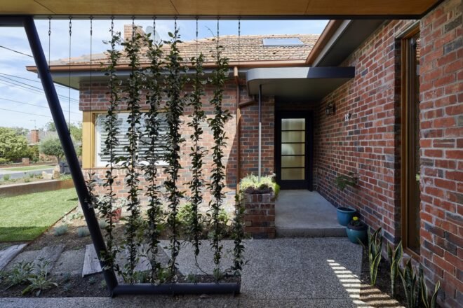 brick lines the home's exterior with plants surrounding the entrance