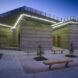 rammed earth building with green lighting and outdoor benches