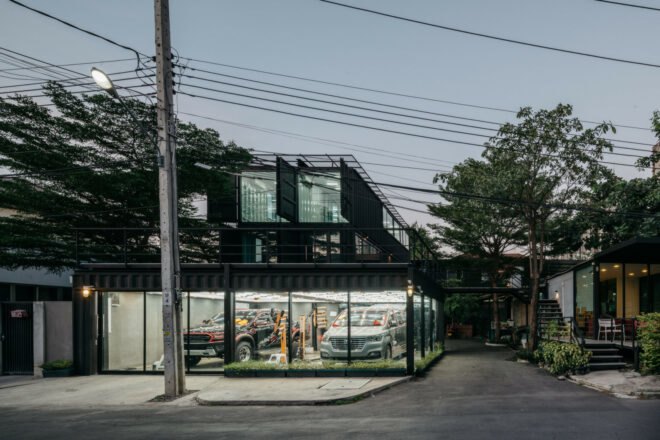 all black shipping container building on corner lot at dusk