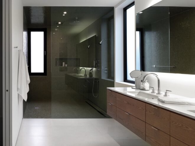 white bathroom with wood cabinets and dark-tiled shower