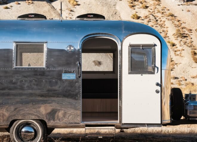 silver airstream trailer with door open in desert