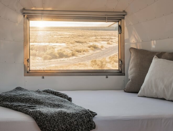 bedroom in airstream trailer with sunlight coming through a large window