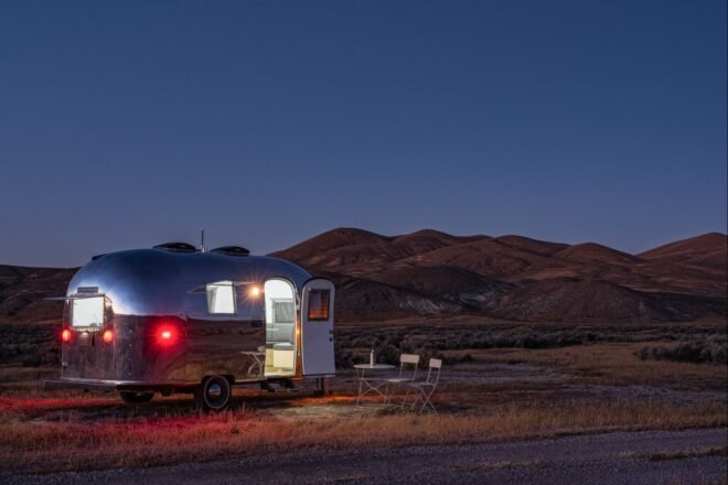 silver airstream trailer with door open at night