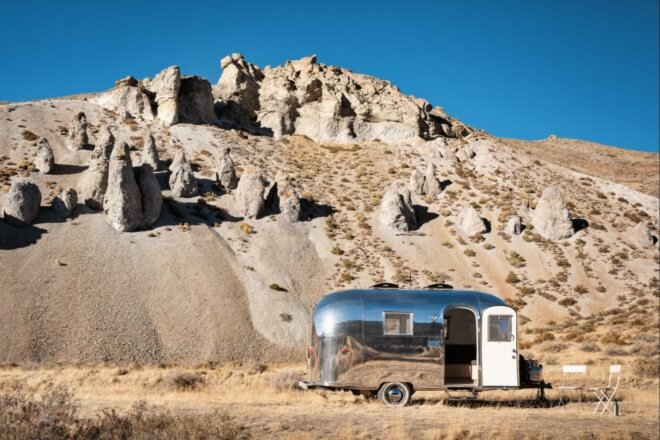 silver airstream trailer with door open near rocky mountain
