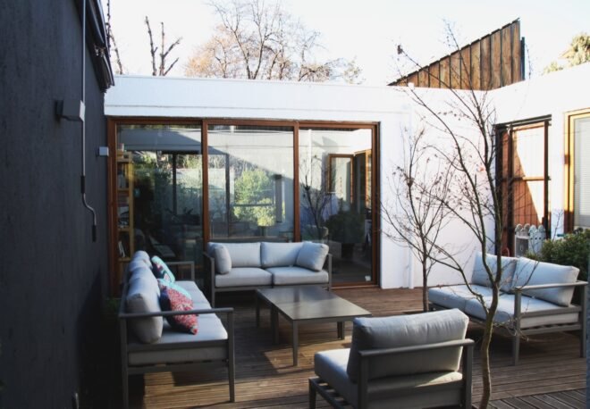 wooden outdoor patio with four gray sofas