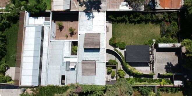 aerial view of concrete home with long, winding, greenery-filled walkway