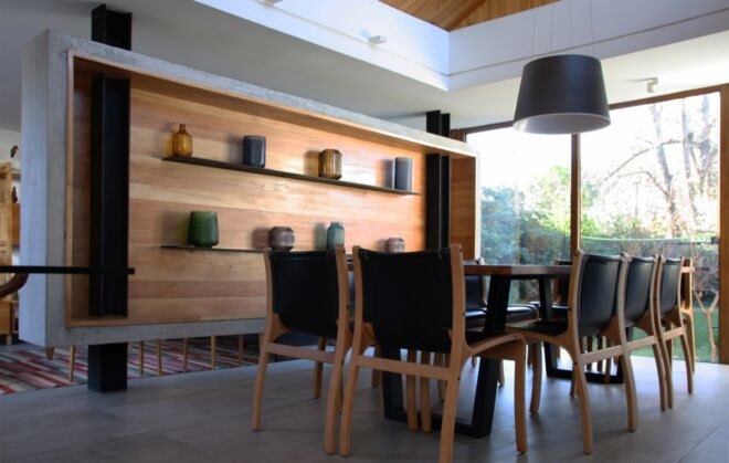 dining room with wood table and wood wall with floating shelves