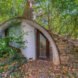 curved hobbit house with green roof