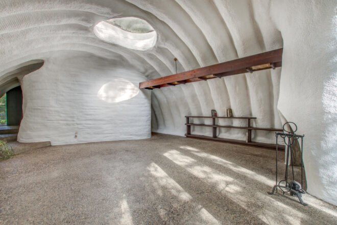 white living room with curved roof and skylight as well as wooden shelves for storage