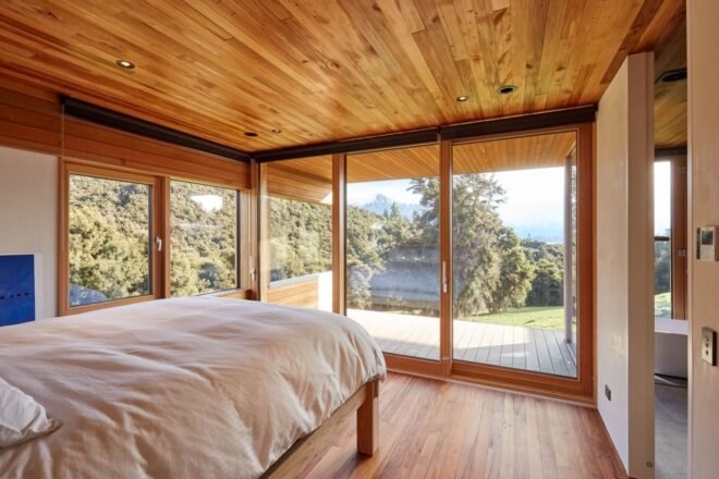 white bed facing windows with views of forest