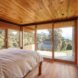 white bed facing windows with views of forest