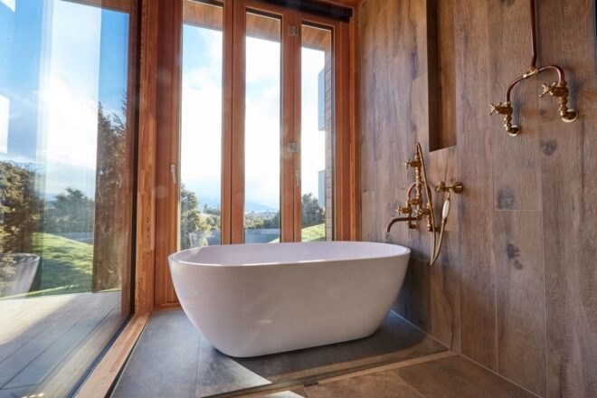 free standing bathtub near full-height windows