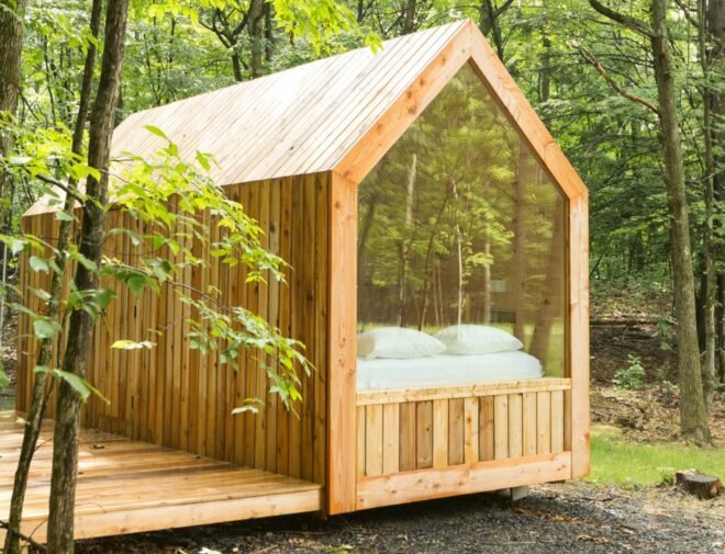 wood cabin with glass wall revealing a bed inside