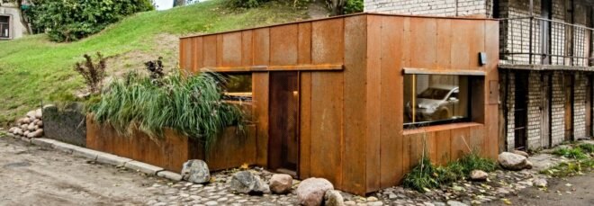 tiny corner garage clad in weathered metal