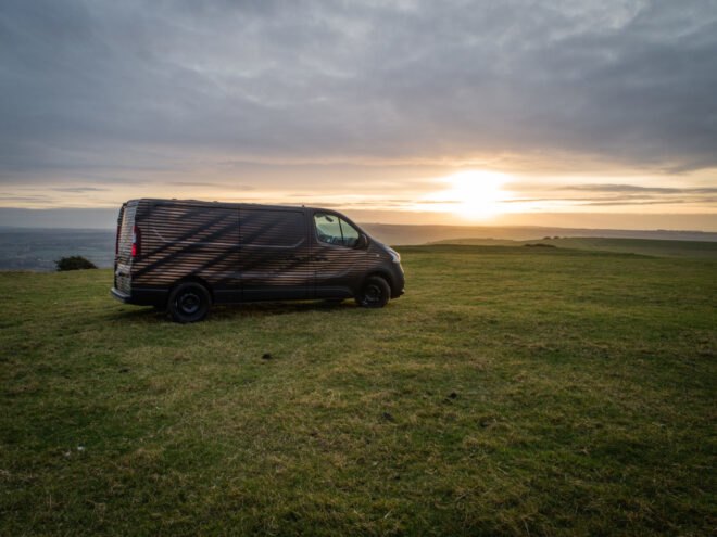 long dark van on expansive green land