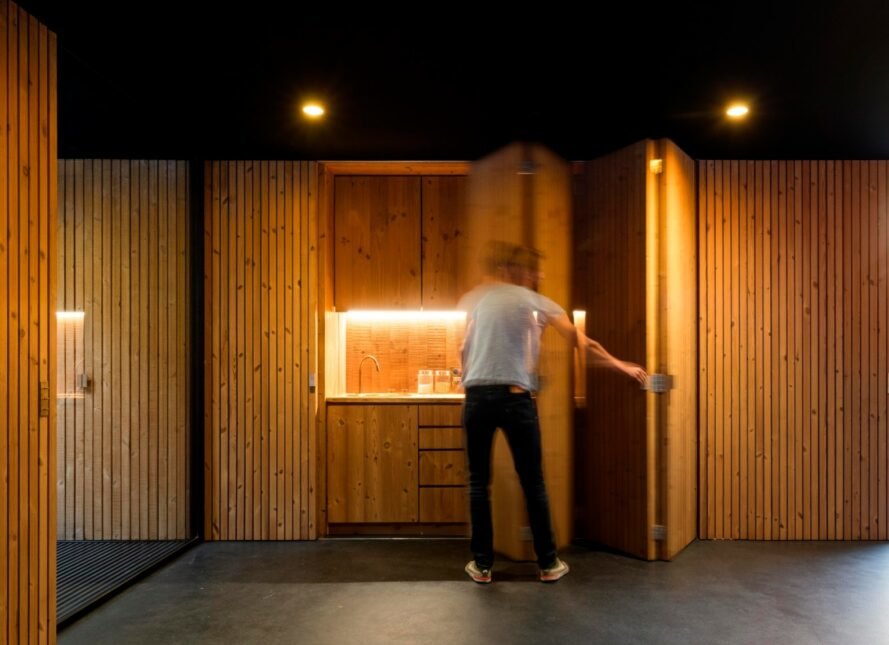 man opening a door inside timber-lined room