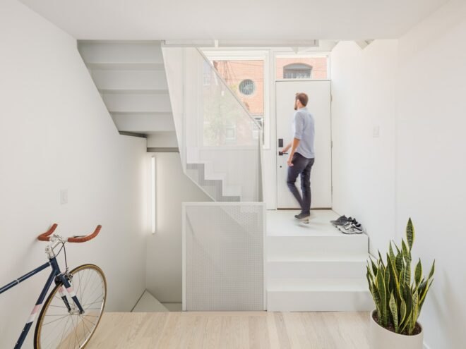 man walking up all-white stairwell