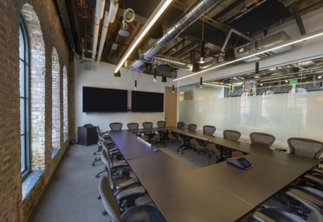 meeting room with large black table inside room with exposed brick wall