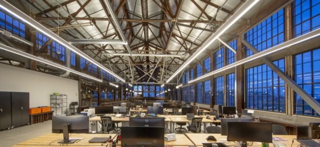 rows of wood desks under rows of bright lights