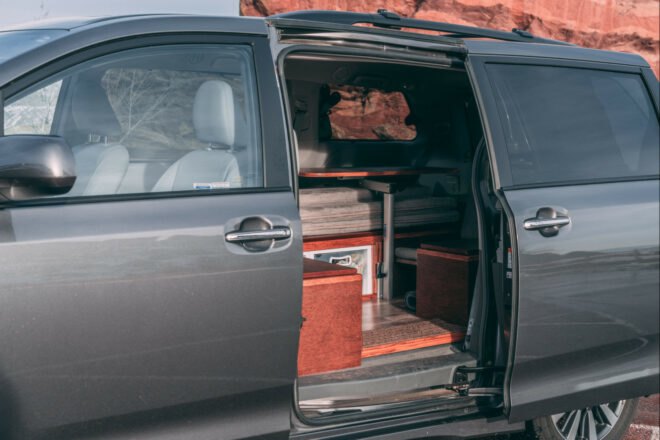 dark camper van with side door open, revealing living space inside