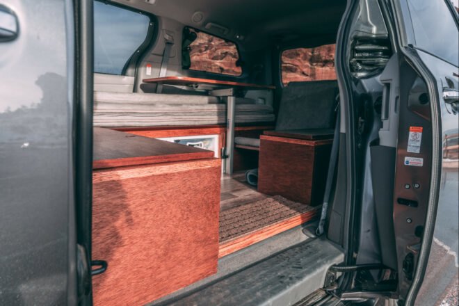 dark camper van with side door open, revealing living space inside