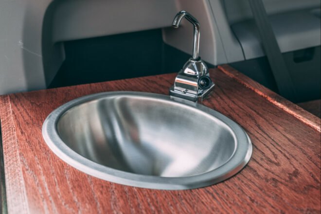 a small silver sink in wooden countertop