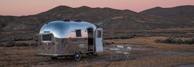 silver airstream trailer with door open at sunset