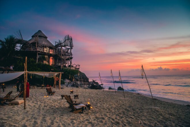 wood building with thatched roof by the beach at sunset