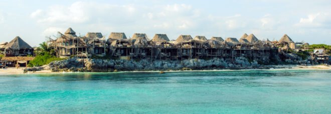 line of wooden buildings with thatched roof by the sea