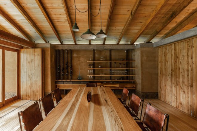 long wood dining table in room with rammed earth walls