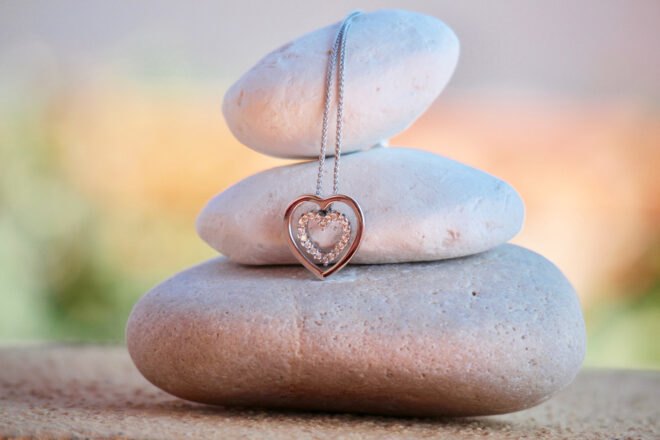 heart-shaped necklace draped over stack of rocks