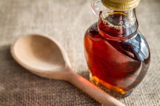 wood spoon next to glass bottle of maple syrup
