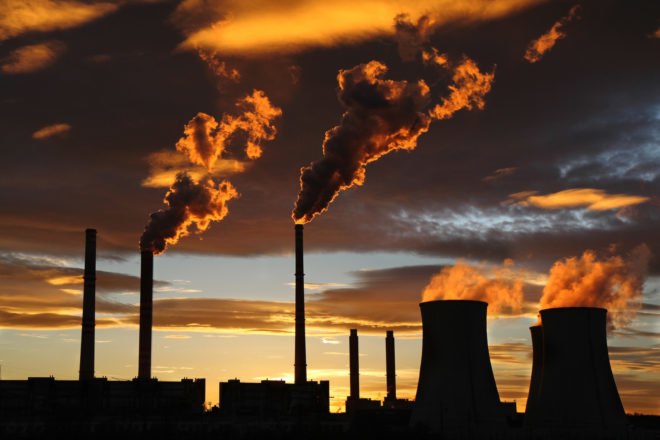 power plant with emissions escaping during sunset