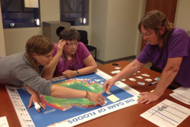 adults gathered around board game
