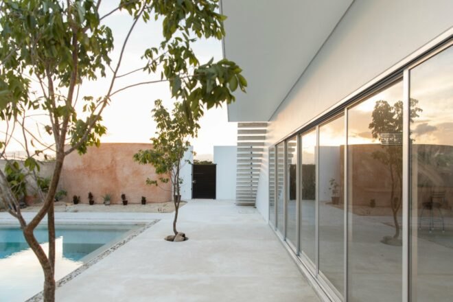 all-white home with large sliding glass doors leading out to swimming pool