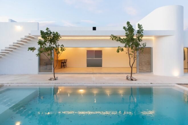 white home behind two trees and a swimming pool
