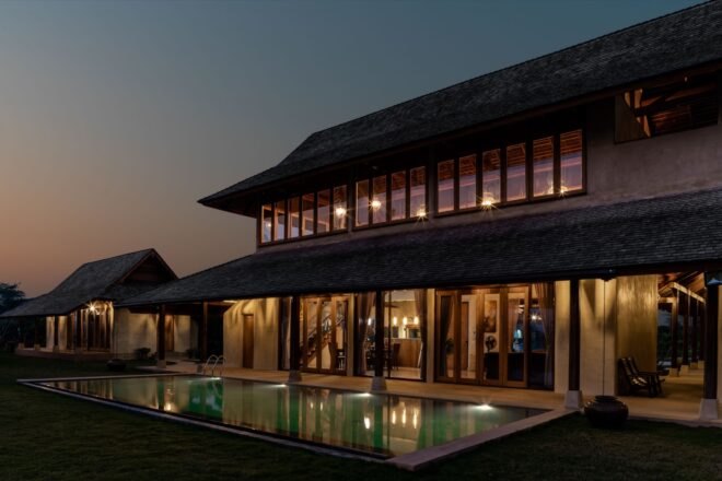 two story adobe brick home with swimming pool all lit up at night