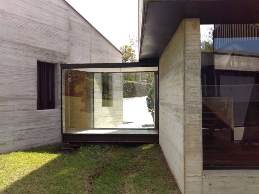 glass-enclosed hallway between concrete homes