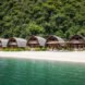 series of thatched roof huts on a remote beach