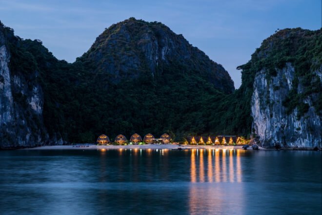 series of thatched roof huts on a remote beach in evening time