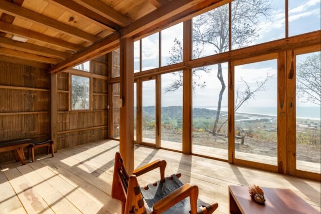 wood-lined room with chairs facing a glass wall with views of the sea