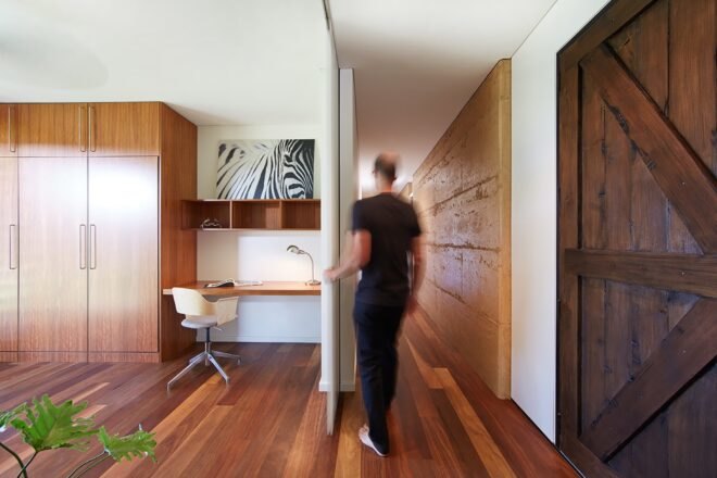 person opening a moving wall revealing a small office space